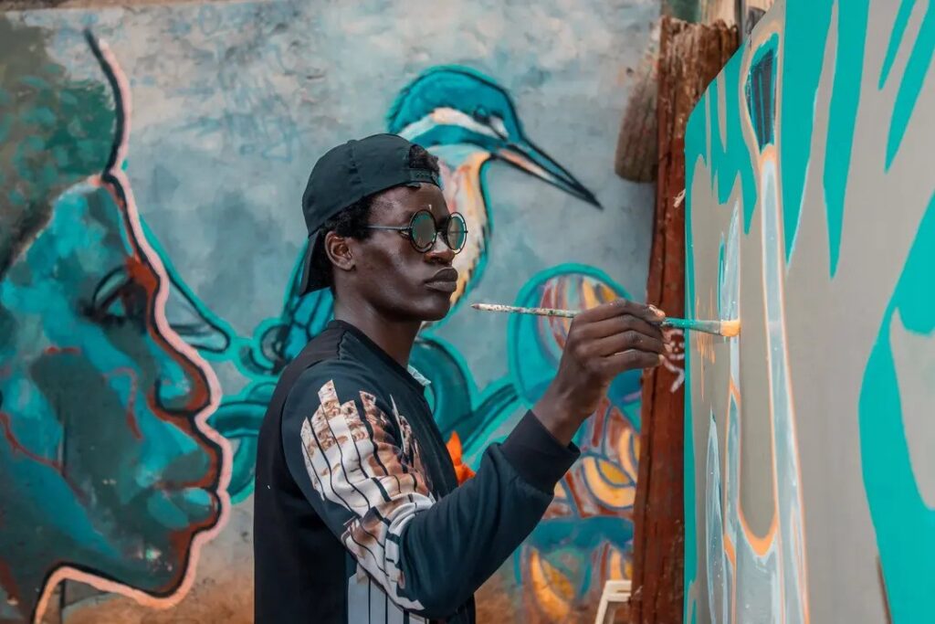 An african young man painting on a wall. image: Pexels/ Derrick Wandera